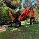 Trabajador de van Beek utilizando unas ramas en una trituradora de ramas naranja marca van Beek.
